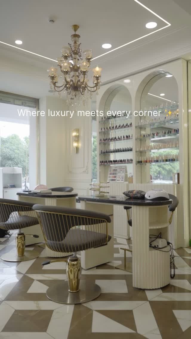 The salon floor: a crystal chandelier, a mirrored wall of nail polish and gold-and-cream styling chairs on a geometric marble floor